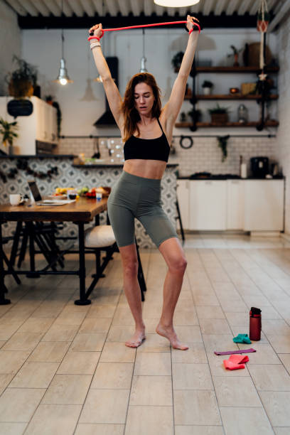 istock Young woman working out at home doing overhead resistance band stretch. 1325782953
