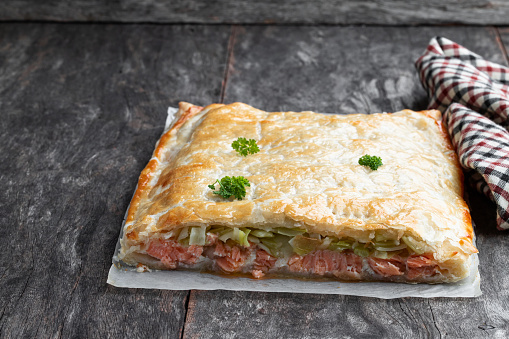 Homemade  salmon wellington with spinach and mushrooms on rustic wooden table