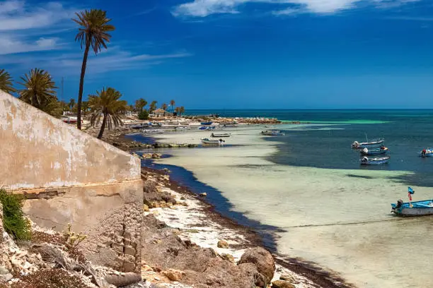 Seascape. Wonderful views of the Mediterranean coast with birch water, white sand beach and a fishing boat. Djerba Island, Tunisia