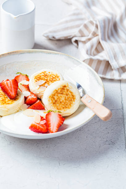 homemade cottage cheese fritters - syrniki with strawberries and yogurt, russian and ukrainian cuisine concept. - cheesecake syrup almond cream imagens e fotografias de stock