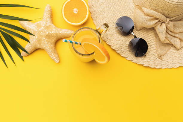 istock Starfish, orange juice, hat and sunglasses on yellow background with copy space 1325789989