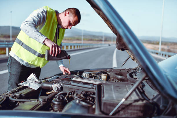 istock Male With Safety Vest Refilling Motor Oil On Old Car After Experiencing Problems On Highway 1325790132