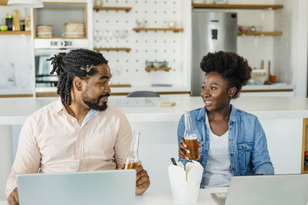 un couple afro-américain travaille à domicile, mange de la restauration rapide et boit de la bière après le travail - after work beautiful people beer beer bottle photos et images de collection