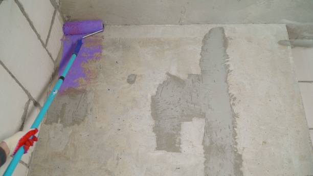 istock Construction work, plastering and wall priming. Builder's hand with paint roller. Copy space. The master paints the wall with lilac paint with a roller. 1325796256