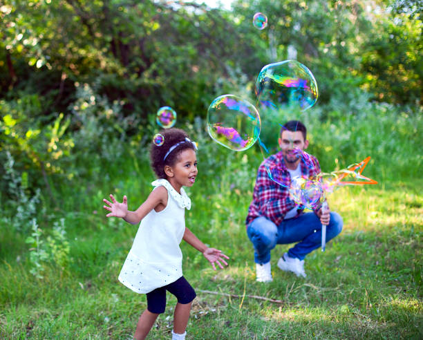 istock Happy father and daughter playing soap bubbles in park. 1325797294