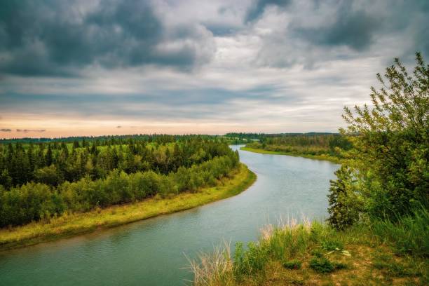 A moody cloudy sky hanging over the Red Deer river in the summertime.