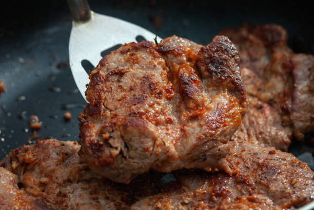 istock Frying pork meat on the pan, closeup 1325804598