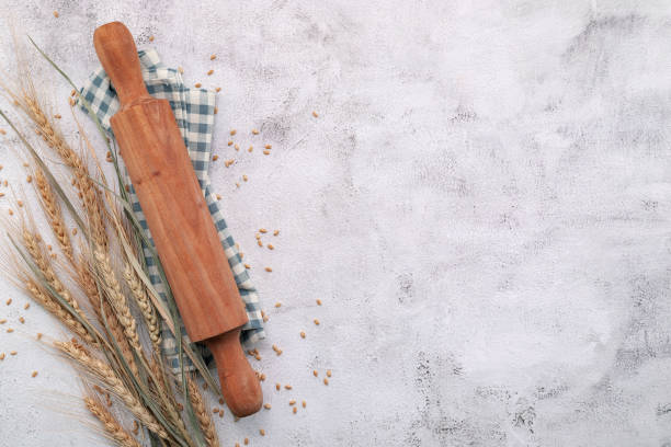 istock Wheat ears and wheat grains setup with rolling pin on white concrete background. 1325811254