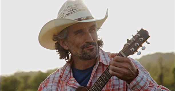istock Cowboy in nature playing the guitar at sunset. Springtime staycation. 1325815398