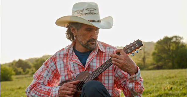 istock Cowboy in nature playing the guitar at sunset. Springtime staycation. 1325815399