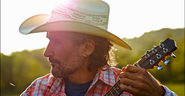istock Cowboy in nature playing the guitar at sunset. Springtime staycation. 1325815404