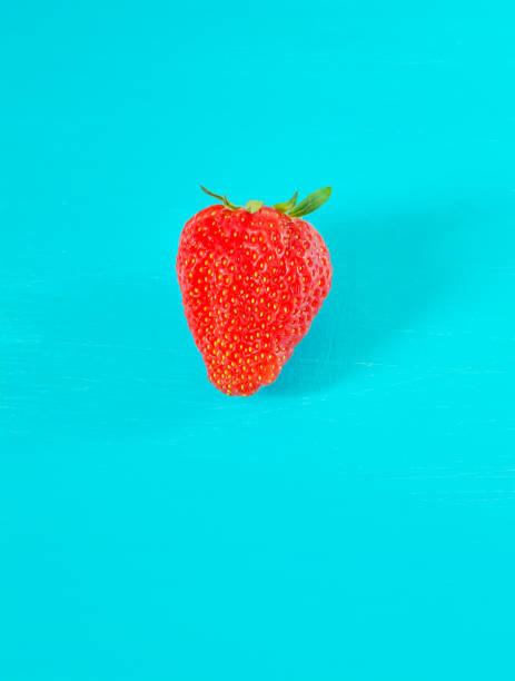 istock One strawberry berry on a turquoise background 1325819085