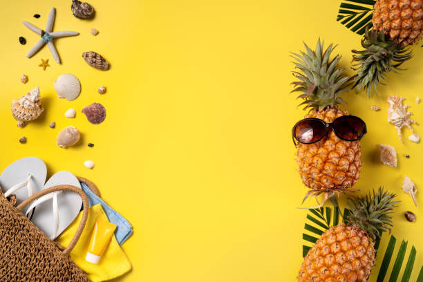 istock Summer fruit background design concept. Beach with shells, pineapple and palm leaves on yellow background. 1325828504