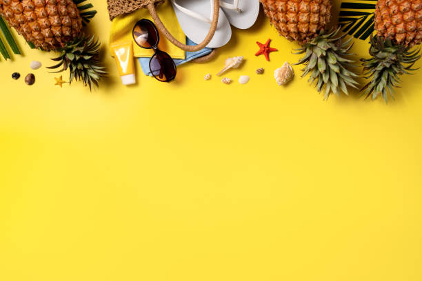 istock Summer fruit background design concept. Beach with shells, pineapple and palm leaves on yellow background. 1325828712