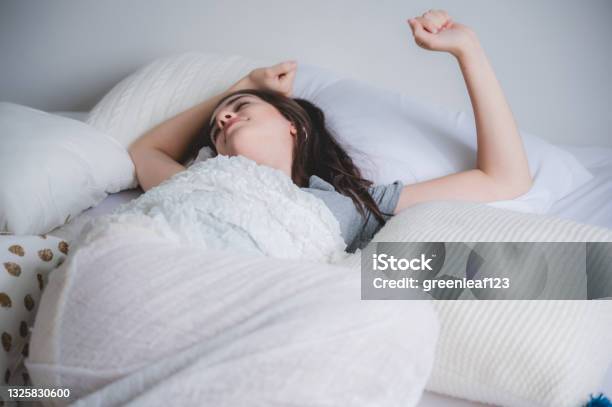 A Young Happy Moring Wake Up Women Stretching On Bed With Fully Rested Warm Sunlight In The Morning White Background Homie Concept Smiling Girl Enjoy Moment On The Bedroom Stock Photo - Download Image Now
