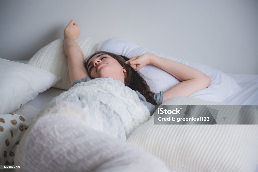 a young happy moring wake up women stretching on bed with fully rested, warm sunlight in the morning, white background, homie concept, smiling girl enjoy moment on the bedroom Bed - Furniture Stock Photo