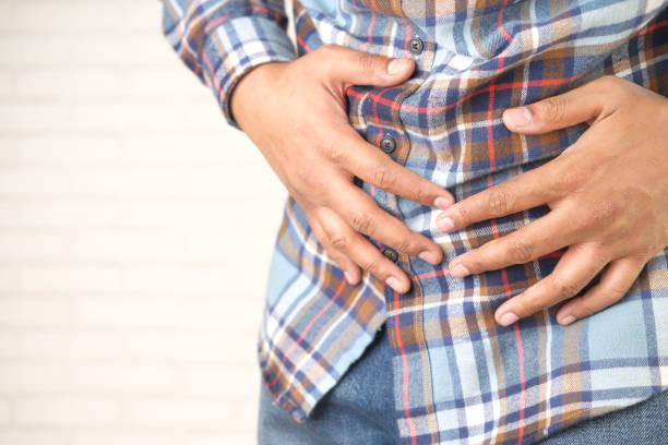 istock young man suffering stomach pain close up. 1325832260