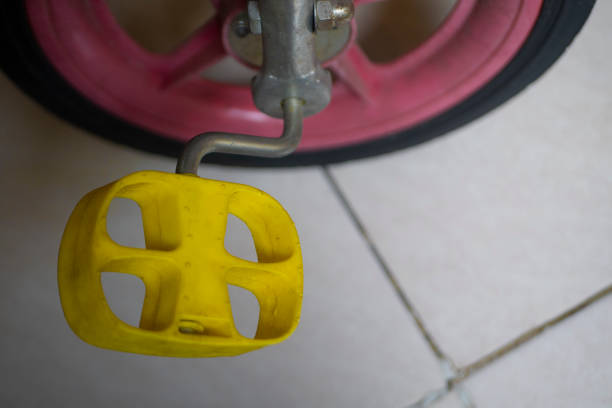 yellow children's bicycle pedals on a pink wheel background