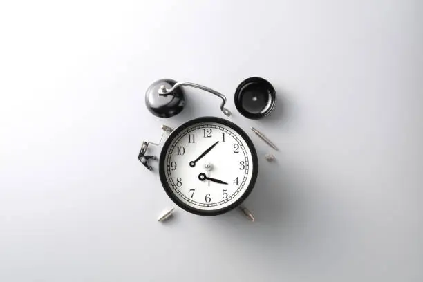 broken black alarm clock on grey background with copy space , time and wilted concept