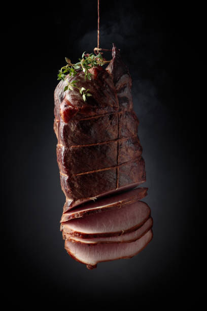 istock Sliced smoked gammon with thyme branches on a black background. 1325844637