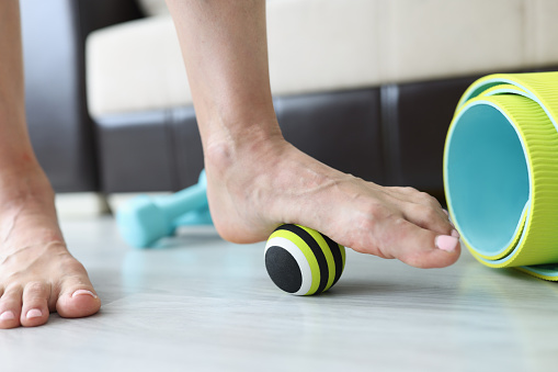 Woman does exercises with ball to correct foot defects and flat feet. Stretching and elimination of painful symptoms in the feet concept