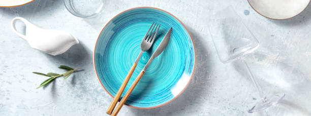 istock Tableware panorama with a vibrant blue plate on a table, with a trendy wineglass 1325850457