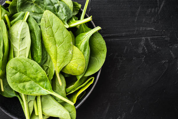 istock Fresh spinach leaves, in bowl, on black stone background, top view flat lay, with copy space for text 1325851257