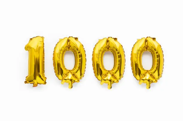 Photo of Number 1000 one thousand golden foil balloon party decor on white background, birthday anniversary