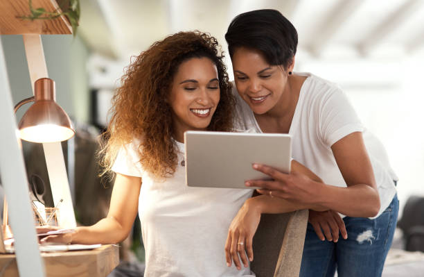istock Shot of a young lesbian couple using a tablet while relaxing in their bedroom 1325852476