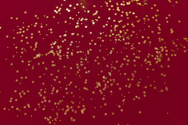 istock Gold glitter stars on a dark red background 1325853106