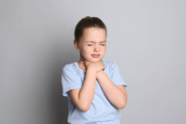 istock Little girl suffering from sore throat on grey background 1325853967