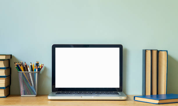 istock Home office desk table background. Empty laptop screen pc on the wooden table with books for work or study. 1325858231
