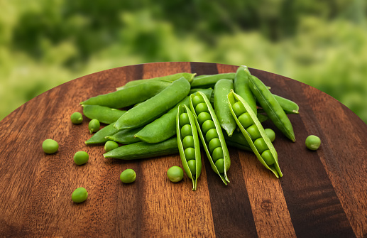 A fresh pea was filmed on a brown wooden cutting board.