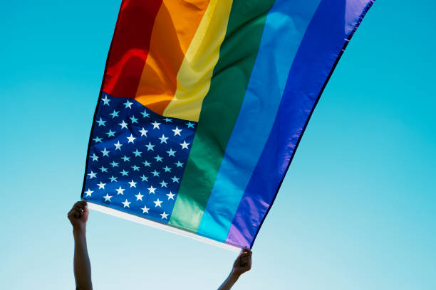 istock person waving a rainbow US flag on the sky 1325860378
