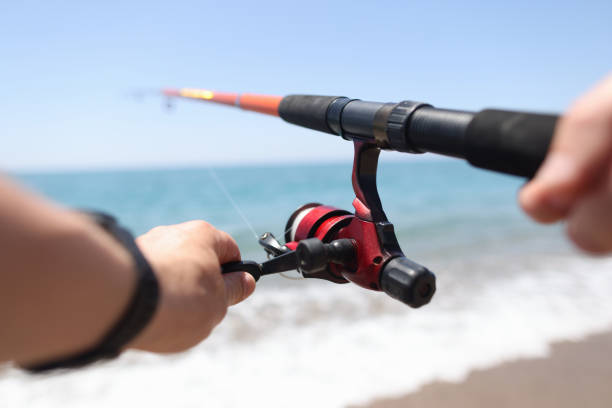 Man is fishing with line on seashore. Male fishing hobby concept