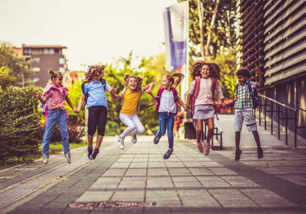 istock Group of elementary age schoolchildren jumping in schoolyard. 1325863123