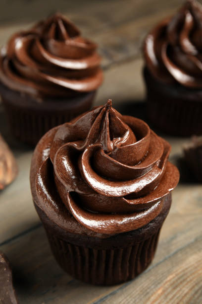 istock Delicious chocolate cupcake with cream on wooden table 1325864477