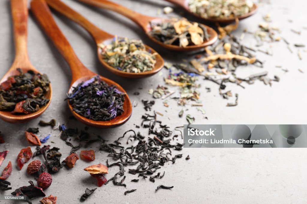 Composition with different teas and spoons on light grey stone table. Space for text Dried Tea Leaves Stock Photo
