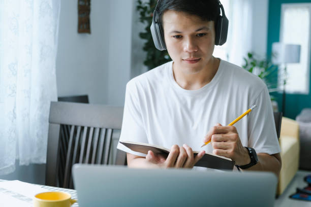 Young collage student using computer and mobile device studying online. stock photo