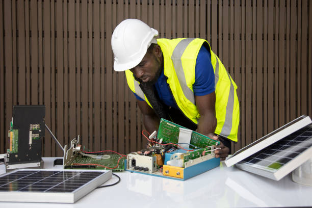 engenheiro afro-americano está trabalhando na criação de circuito de painéis solares para recursos energéticos sustentáveis para uso industrial - electricity control panel engineer electronics industry - fotografias e filmes do acervo