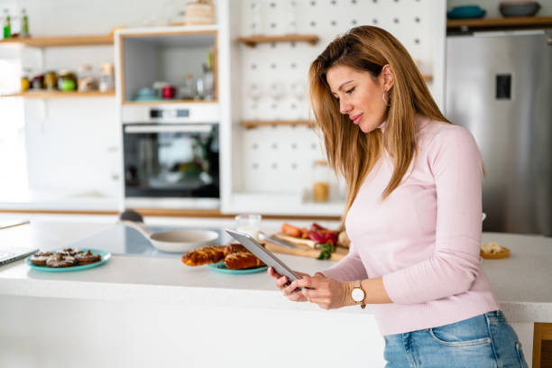 istock Smiling beautiful woman looking at recipe on digital tablet 1325868287