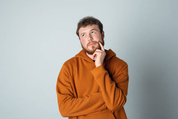 istock Thoughtful bearded young man deep thinking, looking up with pondering face, making choice, wearing stylish hoodie 1325870377