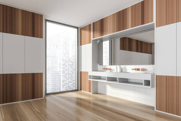 istock Modern design bathroom interior with double sink countertop, bronze faucets. Panoramic window with skyscrapers city view. Wood and white tile walls. Public wc hands wash concept. 1325872017