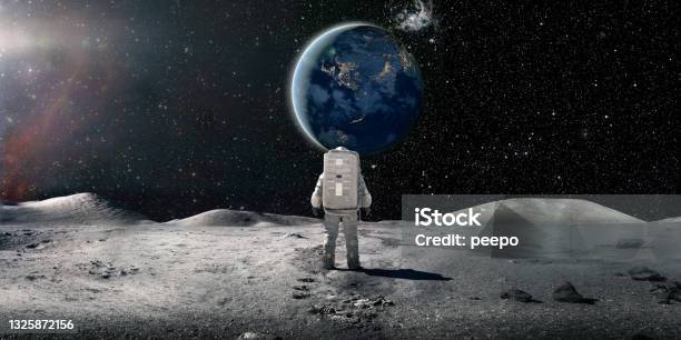 Lone Astronaut In Spacesuit Standing On The Moon Looking At The Distant Earth Stock Photo - Download Image Now