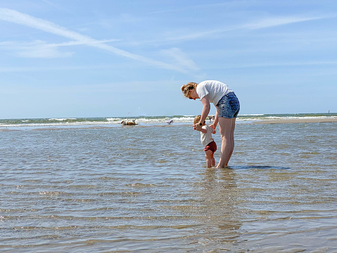 Young mother with her baby girl at the IJmuiden beach on a warm sunny day
