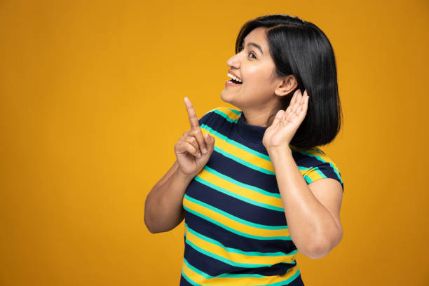 retrato de mujeres jóvenes con el pelo corto de pie aisladas sobre fondo amarillo:- foto de archivo - hand to ear fotografías e imágenes de stock