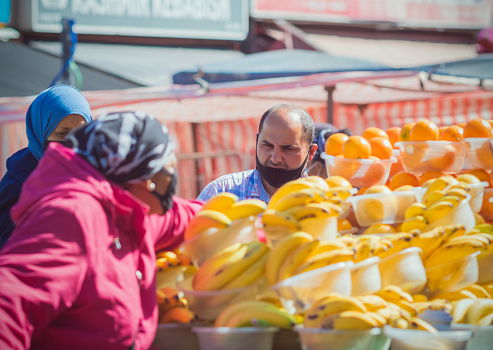 London, UK - 27 May, 2021 - Customers with face masks shopping at a fruit stand at Ridley Road Market