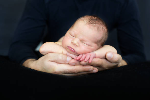 istock Beautiful baby boy, sleeping peacefully in fathers hands, infant sleeping 1325877487