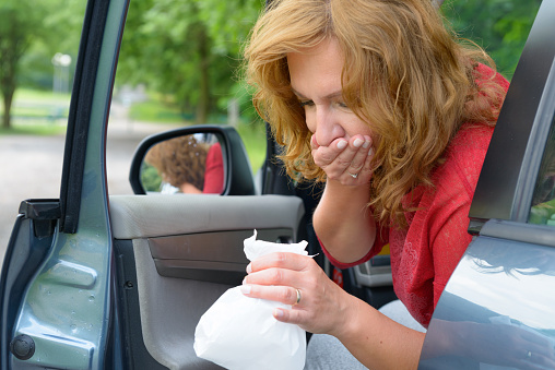 Woman suffering from motion sickness in a car and holding sick bag
