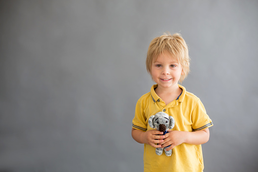 Little toddler child, blond boy, playing with handmade cute little stuffed knitted toy